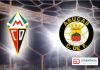 Escudos, de el CD Mensajero y de el Arucas CF, y tras de ellos una portería. Foto nocturna.
